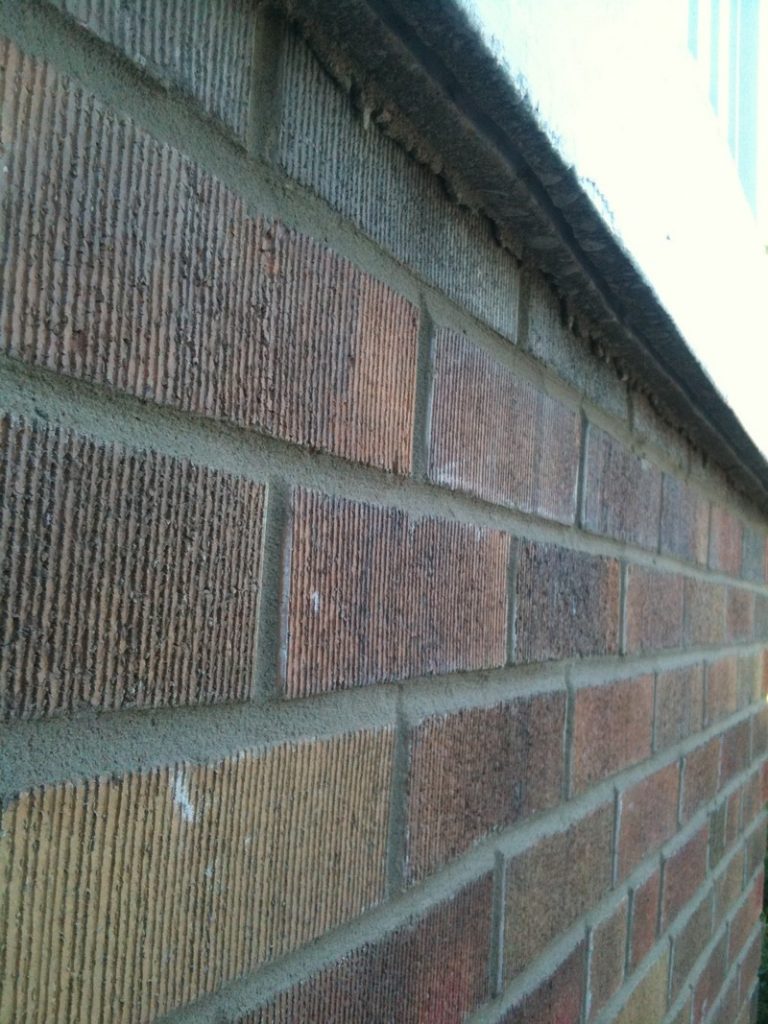 Close-up of a brick wall with freshly repointed mortar joints after tuckpointing