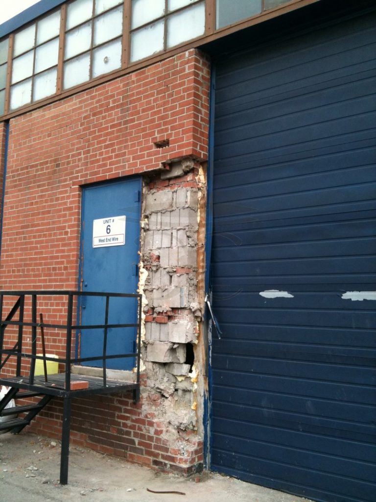 Brick wall beside a loading-dock door with a section opened up to the bare backing