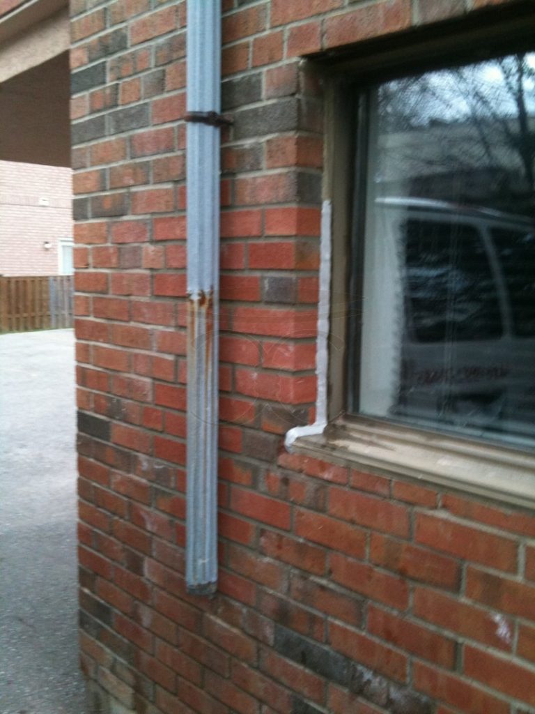 Brick wall beside the window rebuilt along the downspout