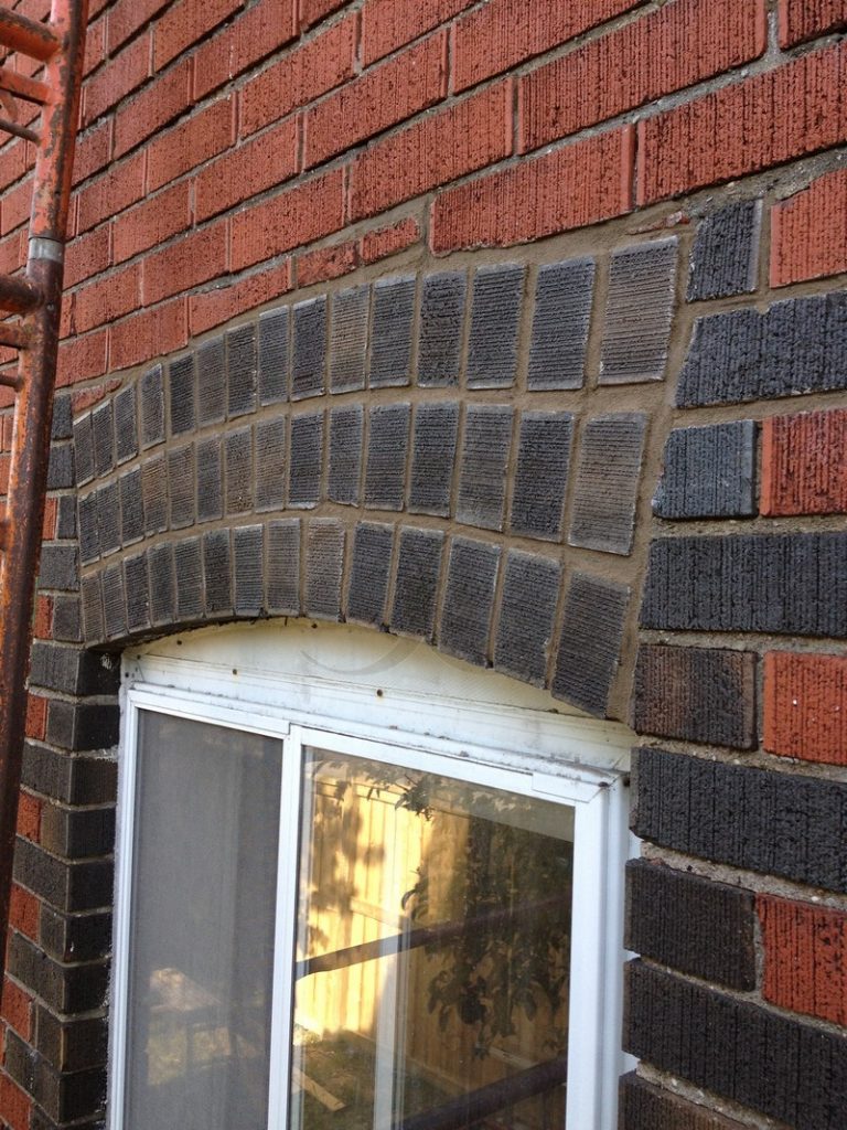 Close view of the dark brick arch above the basement window