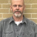 Brian Cummins, owner and lead mason of Cummins Restorations, standing in front of a brick wall