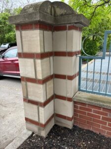 Rebuilt gate pillar in banded red brick and limestone with a stone cap