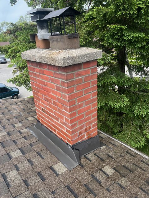 Repointed red brick chimney with clean mortar joints, new flashing and a concrete crown