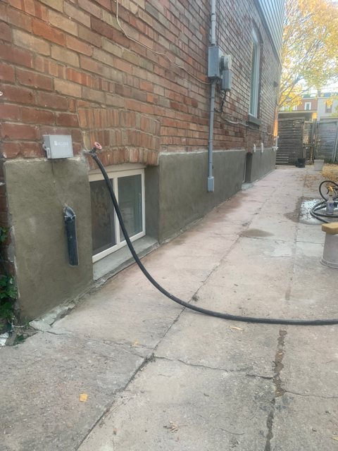 Smooth new parging on the foundation below a red brick wall