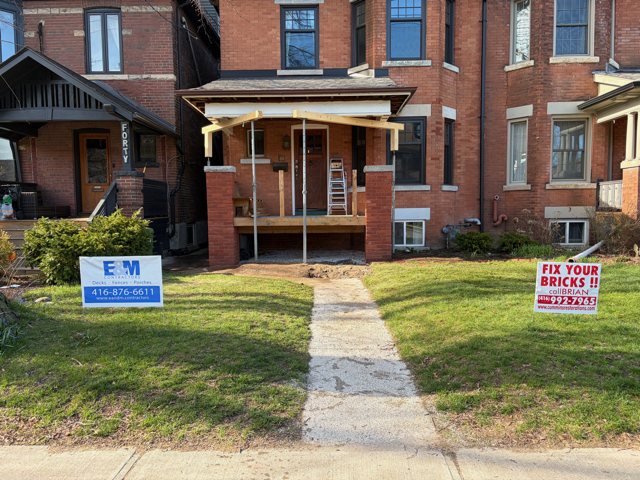 Finished red brick porch pillars on a brick house, with a Cummins Restorations lawn sign out front